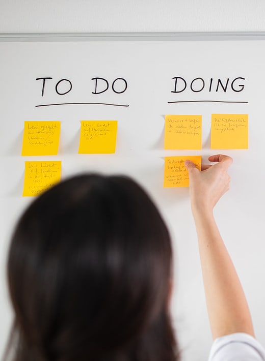 Kontakt und Hilfe Eine Mitarbeiterin arbeitet an einem Kanban-Board, das eine to-do-Liste abbildet