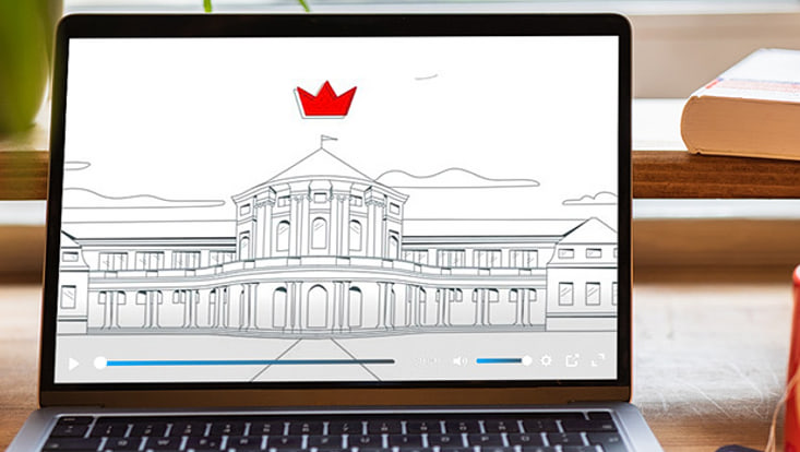 Auf einem Laptop läuft ein Video, das Standbild zeigt das Hauptgebäude der Uni Hamburg als Strichzeichnung. Über ihr schwebt eine kleine rote Krone.