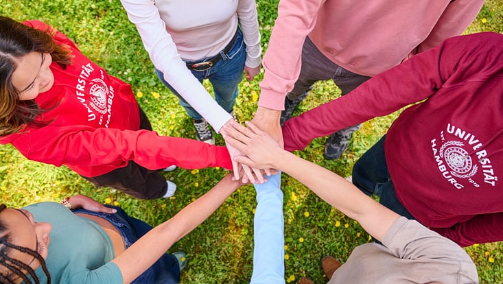 Junge Menschen bilden einen Kreis und legen ihre Hände in der Mitte übereinander