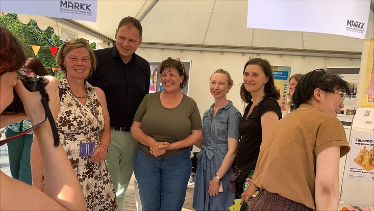 Eine Gruppe von Personen, darunter auch der Präsident Prof. Dr. Hauke Heekeren, die beim Campus Fest vor einem Stand stehen.