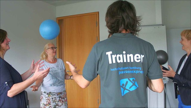 Eine Gruppe macht Sport mit einem Ball im Büro.