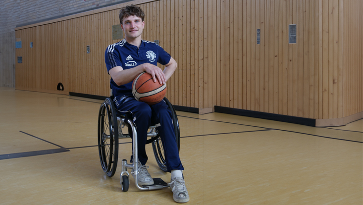 Auf dem Foto sieht man den Rollstuhlbasketballer Luc Weilandt auf dem Basketballfeld im Trikot und einem Basketball in der Hand.