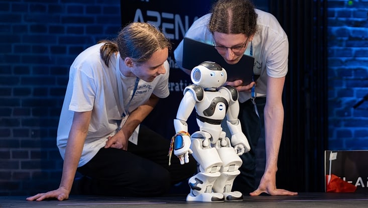 Teilnehmende der „KI-Arena“ mit einem Roboter