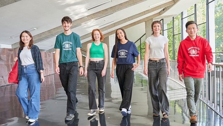 Sechs Studierende laufen nebeneinander im Audimax