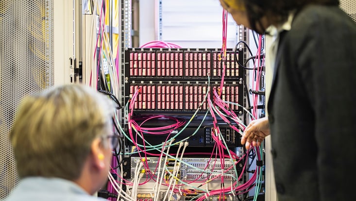 Zwei Mitarbeitende vor einem zentralen Server