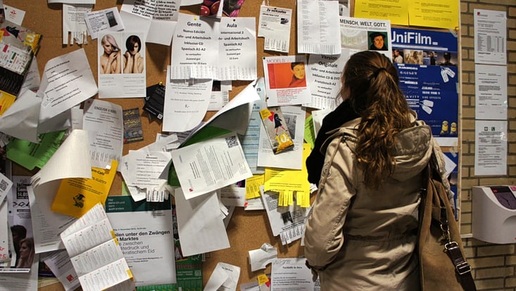 Eine Frau steht vor einer Pinnwand mit vielen Zetteln.