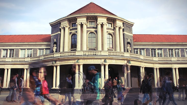 Long exposure shot of people walking in front of the main university building.