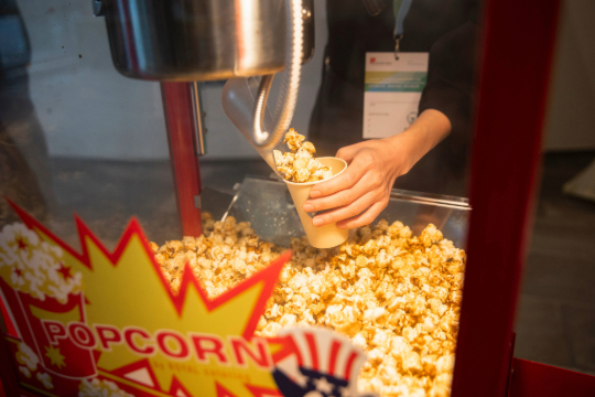 260324_Smart_Transformation_Lab_Esfandiari_4834 Nahaufnahme der Popcornmaschine. Eine Kollegin füllt gerade frisches Popcorn in einen Becher.