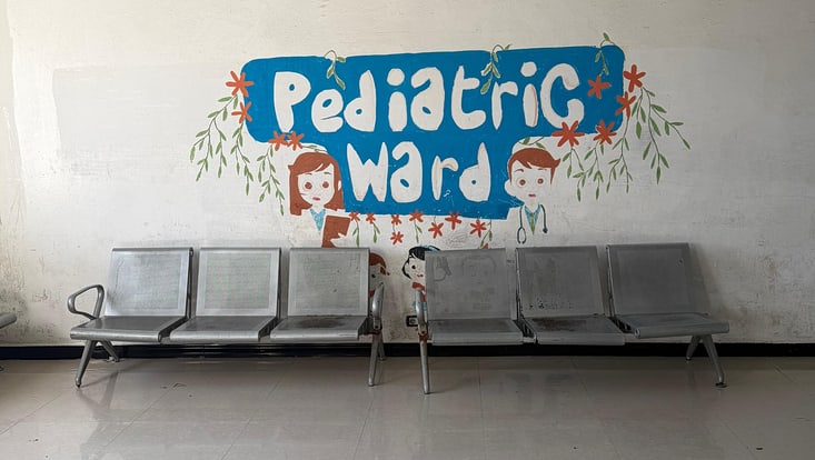 Symbolfoto von Stühlen unter einem Wandbild mit der Aufschrift "Pediatric Ward"