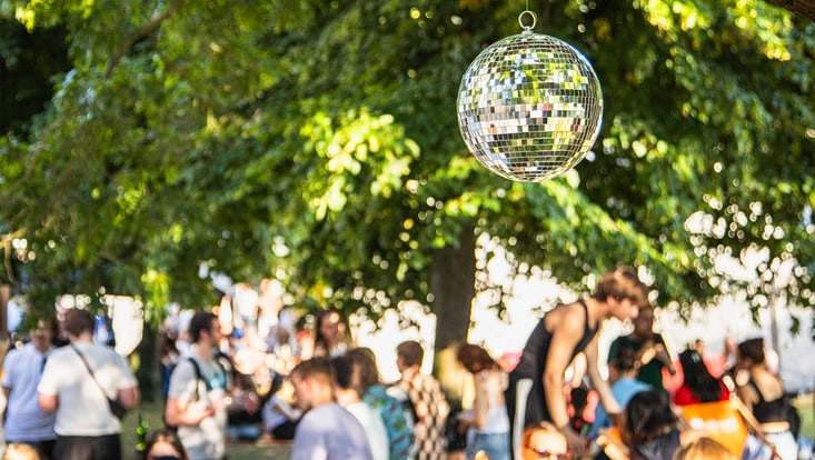 Eine Discokugel auf dem belebten Campus bei einem der vergangenen Campusfeste. Im Hintergrund sind Studierende zu sehen.