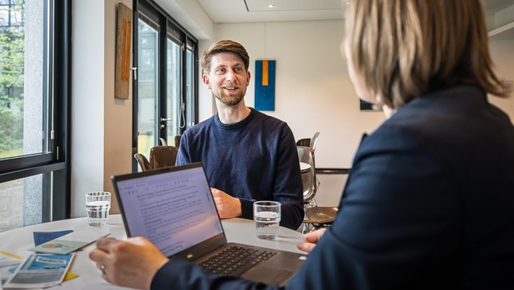 Beratungsgespräch zwischen zwei Personen an einem Tisch.