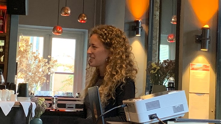 Person in einem Café, daneben steht ein Laptop und ein Beamer