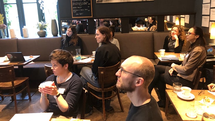 Personen sitzen in einem Café und hören zu