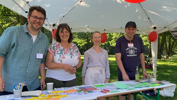 02-02-vernetzung-sc-bahrenfeld-stadteilfeste-20230708-bahrenfeld-uc-(23)-733x414 Vier lächelnde Personen stehen an einem Informationsstand