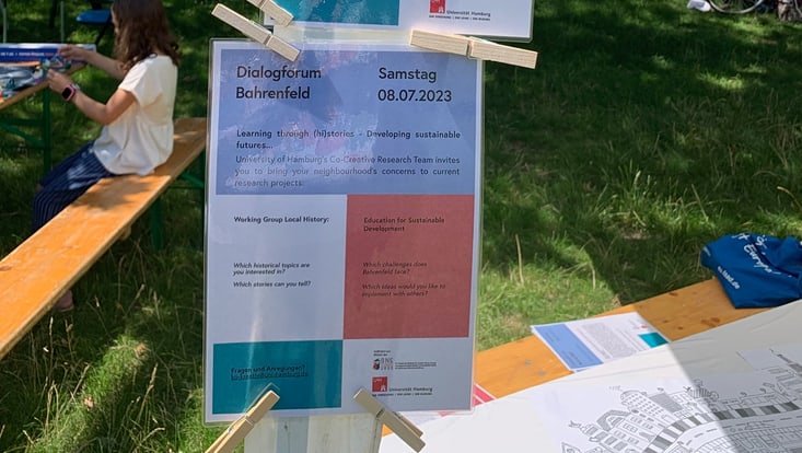 Programm mit Schriftzug „Dialogforum Bahrenfeld“ ist mit Wäscheklammern an einem Pavillon festgemacht
