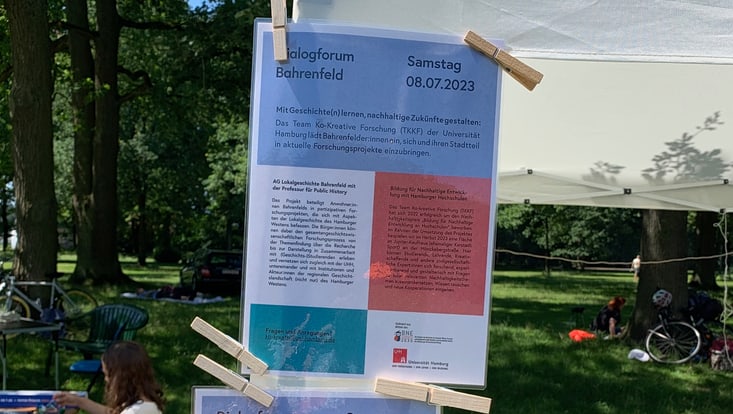 Programm mit Schriftzug „Dialogforum Bahrenfeld“ ist mit Wäscheklammern an einem Pavillon festgemacht