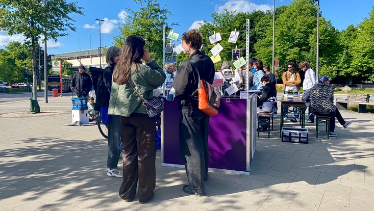 Personen stehen vor einem Informationsstand und unterhalten sich