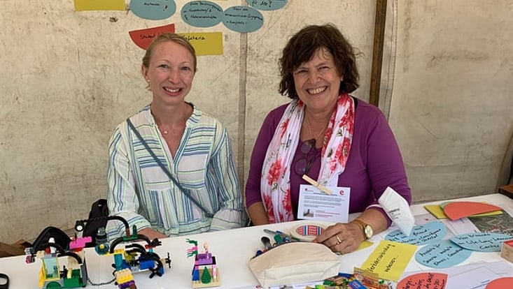 Foto der beiden Mitarbeiterinnen Claudia Mendes und Ursula Caser an einem Festival-Stand