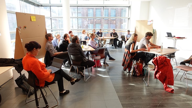 04-03-koord-transferfonds-slider-2023-02-231017-transferfkickoff-cuhh-tkkf-33-733x414 Personen sitzen an Tischen in einem Raum, einige schreiben, im Hintergrund steht eine Pinnwand