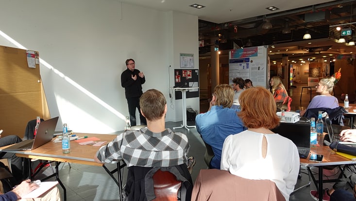 04-03-koord-transferfonds-slider-2023-03-231017-transferfkickoff-cuhh-tkkf-10-733x414 Personen sitzen an Tischen in einem Raum, einige schreiben, im Hintergrund steht eine Pinnwand