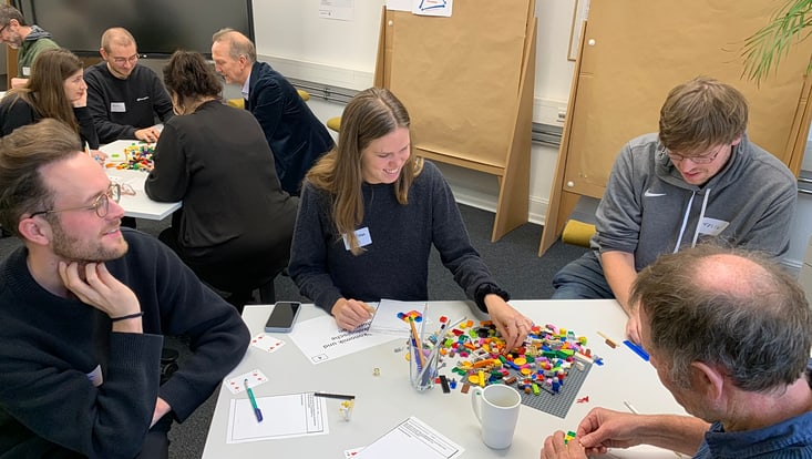 04-03-koord-transferfonds-slider-2024-04-2024-11-27-transferfonds24-kick-off-cucaser-(18)-733x414 Personen sitzen an Tischen und bauen etwas mit Legosteinen