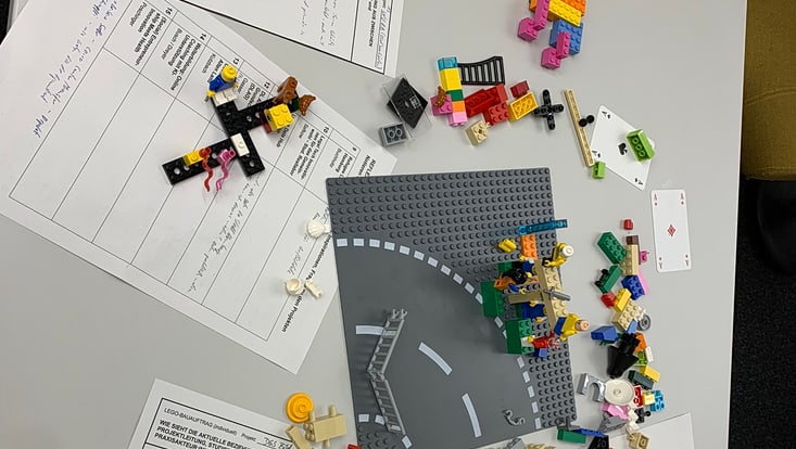 04-03-koord-transferfonds-slider-2024-05-2024-11-27-transferfonds24-kick-off-cucaser-(29)-733x414 Legostraße und gebaute Legofiguren auf einem Tisch mit weiteren Arbeitsmaterialien