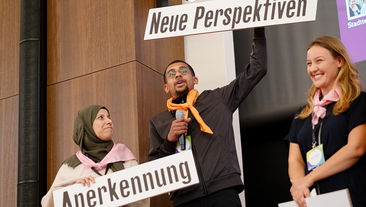 Teilnehmende des Forum Citizen Science auf einer Bühne halten Schilder mit den Aufschriften Anerkennung, Neue Perspektiven