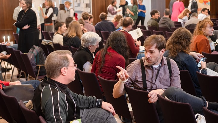 Teilnehmende des Forum Citizen Science 2024 sitzen im Publikum und unterhalten sich