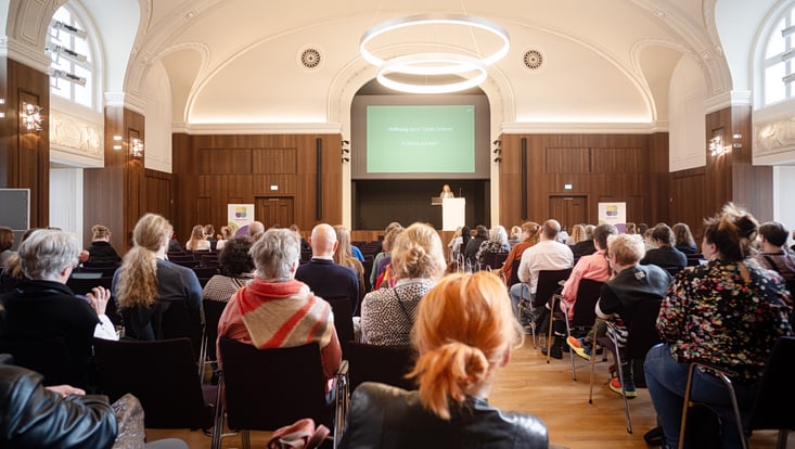 Publikum der Abschlusskeynote des Forum Citizen Science 2024 von hinten, vorne Bühne mit Sprecherin