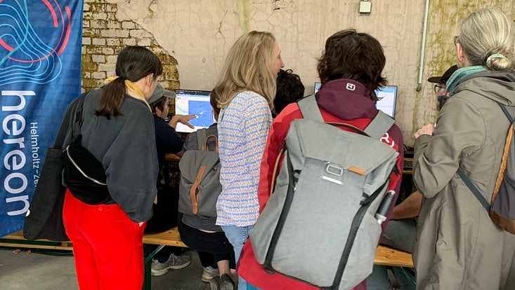02-05-vernetzung-festivals-sliderasphaltsprenger_2-733x414 Personen stehen vor zwei Computern und schauen auf die Bildschirme, eine Person zeigt auf einen der Bildschirme und erklärt etwas