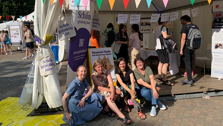 02-05-vernetzung-festivals-ebene-2-slider-campusfest-cucaser-46-733x414 Team Co-Creation & Engagement sitzt auf Stufen vor ihrem Festivalstand