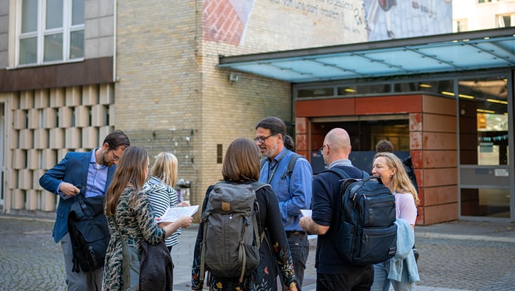 2025-09-19-cmc-t-02-alena-zielinski-(124)-733x414 Eine Personengruppe vor dem VMP9 Gebäude diskutiert miteinander