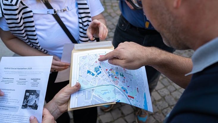 2025-09-19-cmc-t-02-alena-zielinski-(126)-733x414 Eine Person hält einen Stadtplan in der Hand, eine andere zeigt darauf