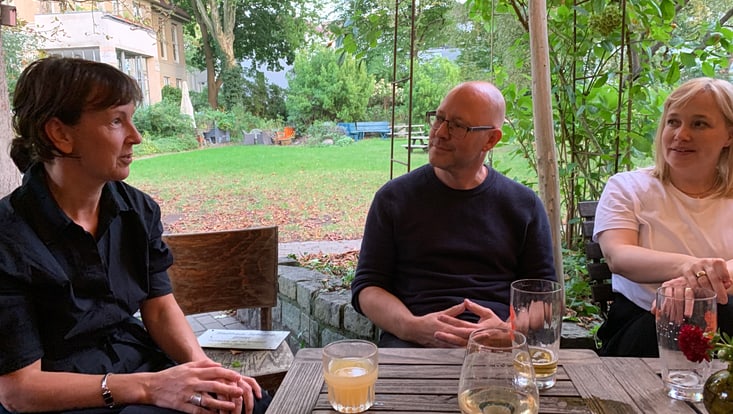 2025-09-19-hbdv-walktalk-cucaser-(14)-733x414 Eine Person spricht, während die anderen Personen am Tisch aufmerksam zuhören