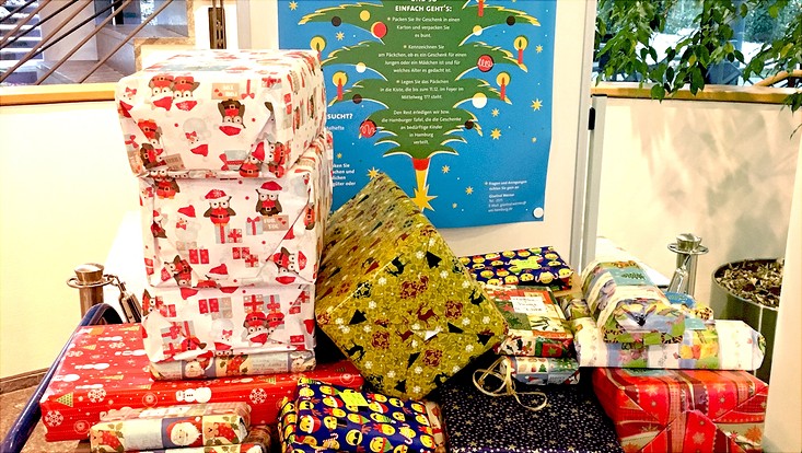 Bunt verpackte Geschenke vor dem Plakat für die Aktion "Umgekehrter Adventskalender"