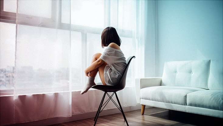 Eine Frau sitzt alleine am Fenster