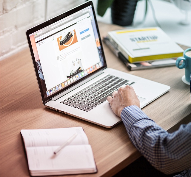 Das Foto zeigt einen Mann der an einem MacBook Pro sitzt.