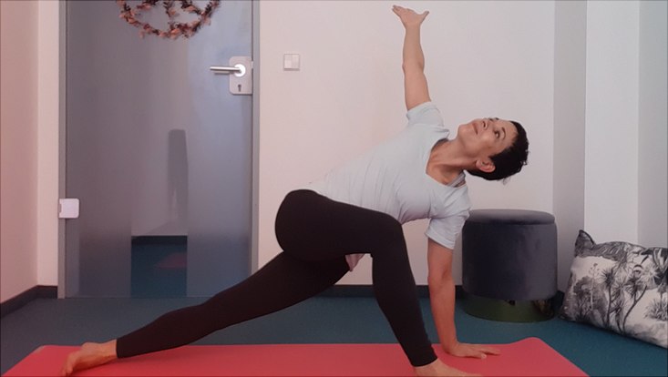 Frau beim Yoga auf roter Yoga-Matte.