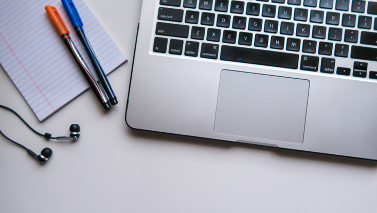 Laptop, Kopfhörer und Stifte auf einem Schreibtisch
