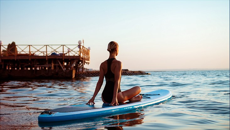 silhouette-beautiful-woman-practicing-yoga-surfboard-sunrise-733x414 Frau sitzt auf Surfbrett