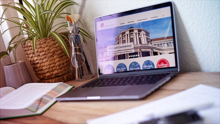 Laptop mit Website der UHH auf Schreibtisch.