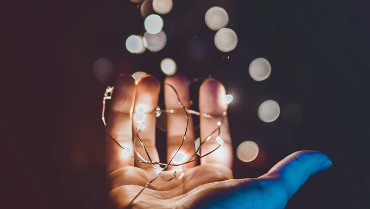 Das Foto zeigt eine Hand mit einer kleinen Lichterkette