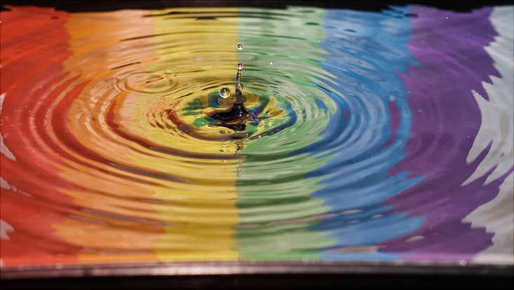 Eine Pfütze in der sich ein Regenbogen spiegelt