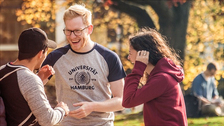 Mehrere Studierende lachen zusammen auf dem Campus.