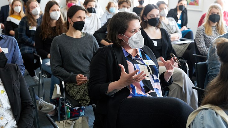 Julia Panzer sitzt im Publikum und stellt eine Frage