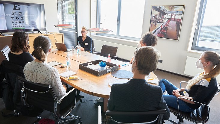 Um einen runden Tisch sitzen die Teilnehmenden des Workshops von Nicola Kuhrt