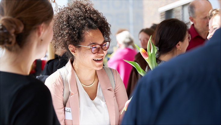 Eine junge Frau lacht im Gespräch mit einem anderen Gast