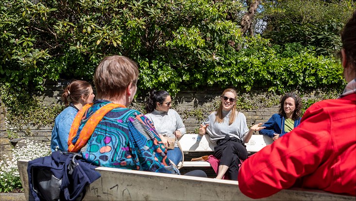 Participants of HRA at the Park sit together with Julia Kölle and Dr. Kerstin Lange on a park bench and talk.