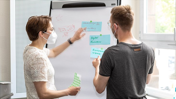 Promovierendentag 2022 Teilnehmende des Promovierendentages hängen Karten an eine Flipchart
