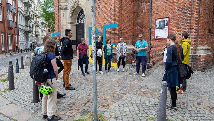HRA Stadtrundgang The participants stand together with the guide in a circle